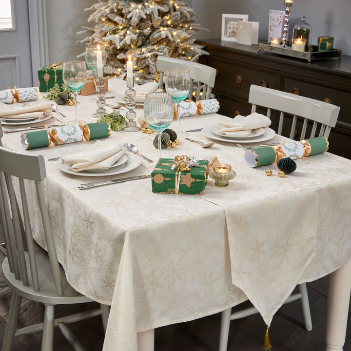 Cream and gold tablecloth measuring 52x70 inches, featuring metallic snowflake motifs.