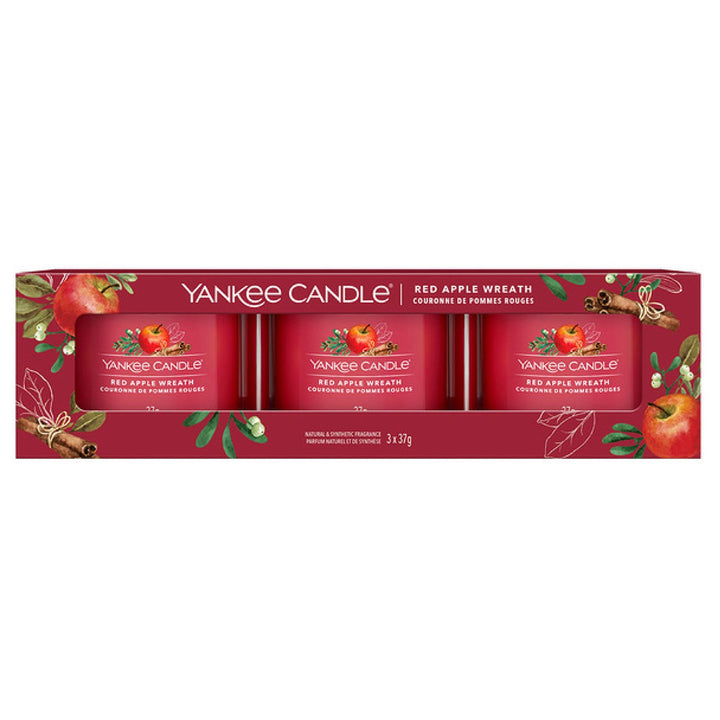 A trio of Apple Wreath Yankee Candle filled votives in vibrant red holders, infusing the air with the delightful aroma of fresh apples and holiday spices, perfect for seasonal gatherings and cosy evenings.