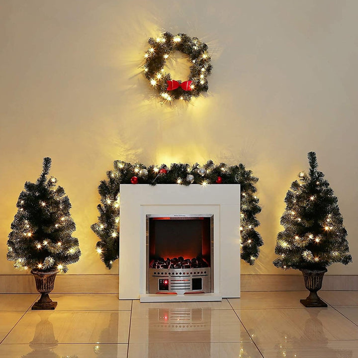 Home interior with beautifully decorated Christmas mantelpiece, featuring pre-lit wreath, garland, and pine trees.
